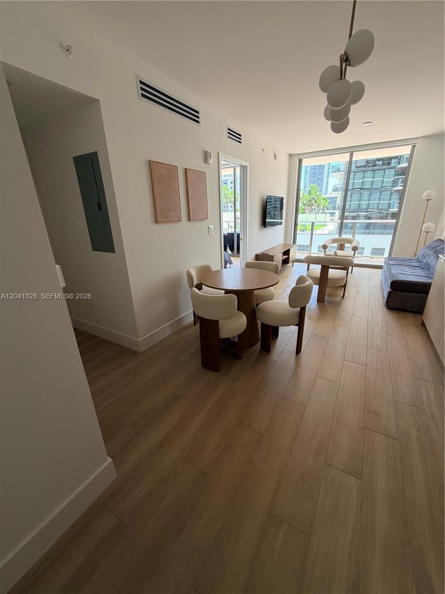 A modern living and dining area features light wood flooring, a round table, and balcony access — 90 NE 32nd St # 707, Miami FL 33137, MIAMI, FL