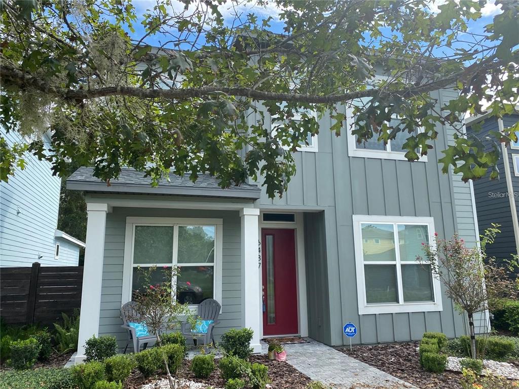 A two-story house with sage green siding, a red front door, and a front porch — 6487 SW 74TH DRIVE, GAINESVILLE, FL