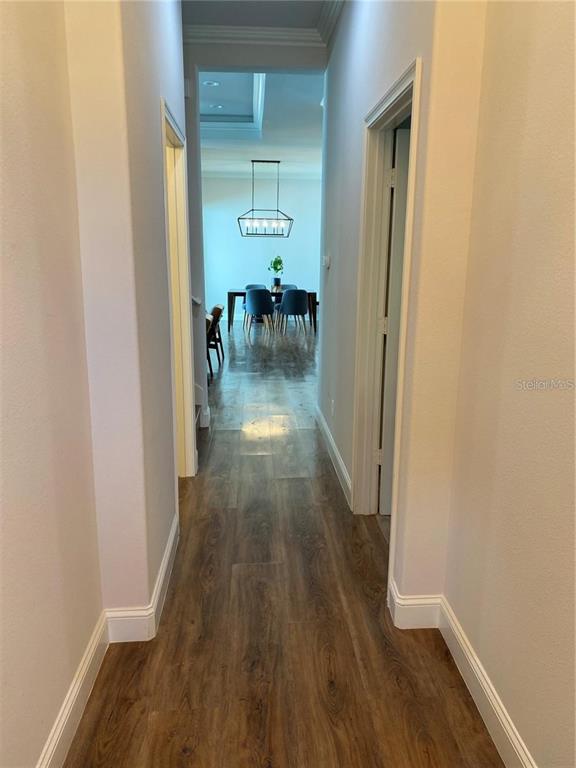 A hallway with wood-look flooring leads to a dining area with a modern light fixture — 6487 SW 74TH DRIVE, GAINESVILLE, FL