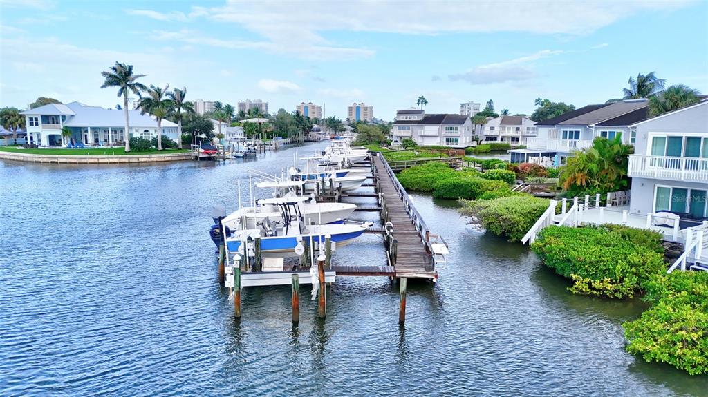An aerial view shows a long wooden dock with several boats moored in a canal — 2486 HARBOUR COVE DRIVE, HUTCHINSON ISLAND, FL