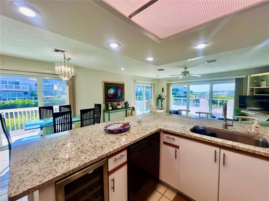 A kitchen with granite countertops and white cabinets overlooks a dining area and outdoor deck — 2486 HARBOUR COVE DRIVE, HUTCHINSON ISLAND, FL