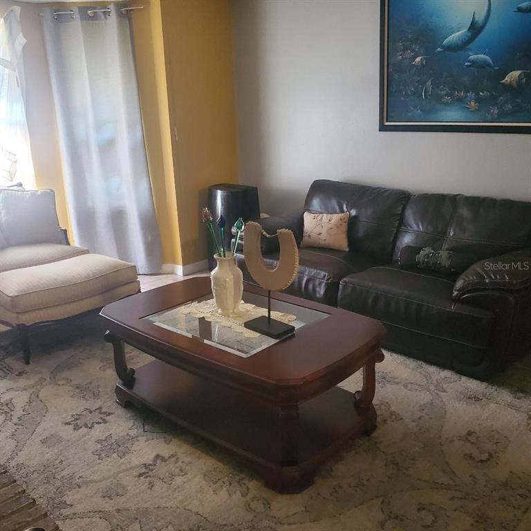 A living room features a brick fireplace, leather furniture, and a patterned area rug — 172 PINEWOOD CIRCLE, KISSIMMEE, FL