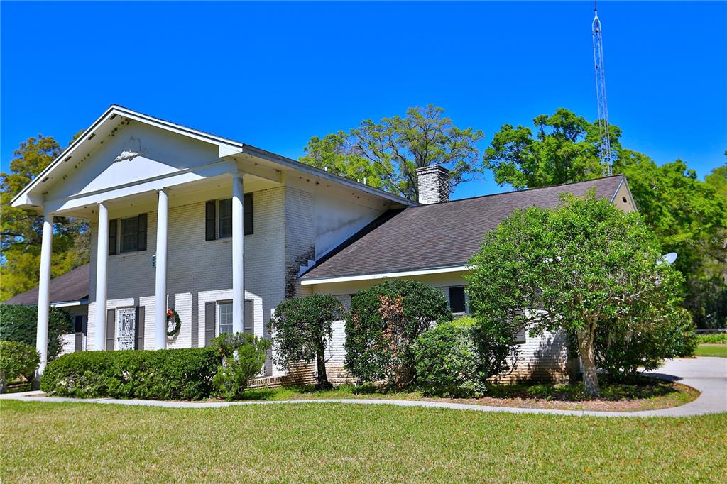 A two-story white brick house features a large front porch with tall columns — 2881 SE 41ST PLACE, OCALA, FL