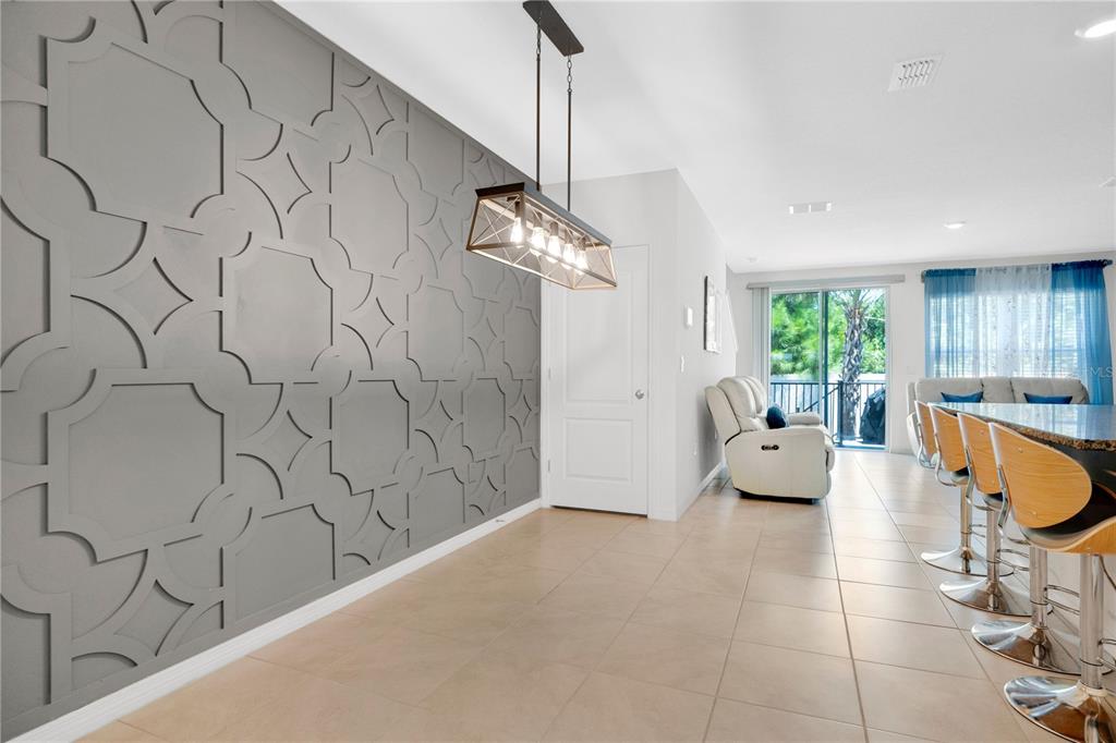 A dining area features a gray geometric accent wall, a modern chandelier, and tile flooring — 33 BELLA OAKS DRIVE, PORT ORANGE, FL