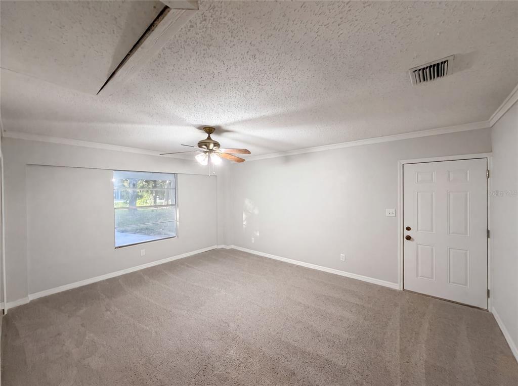 An empty room with gray carpet, white walls, a ceiling fan, and a white door — 827 DORA AVENUE, TAVARES, FL