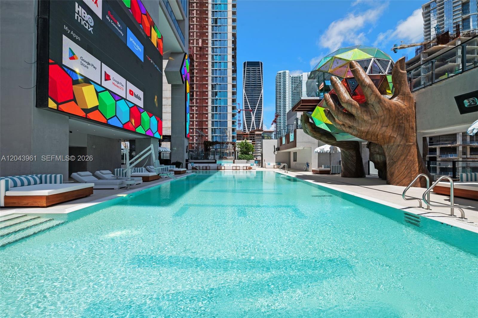 A swimming pool sits on a terrace featuring a large sculpture of hands holding a sphere — 20 NE 11th Street # 4003B, Miami FL 33132, MIAMI, FL