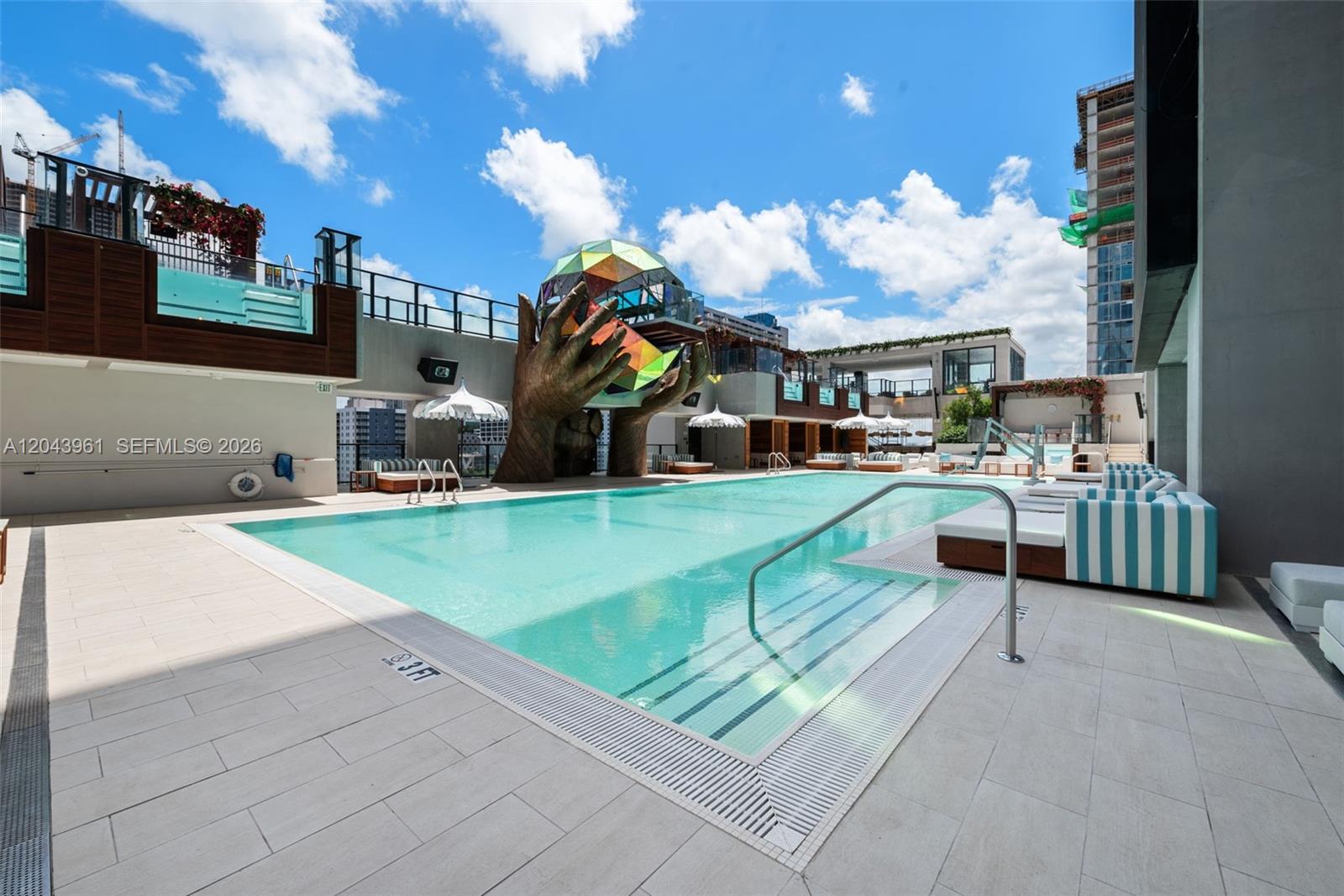 A rooftop swimming pool features a large sculpture of hands holding a geometric glass sphere — 20 NE 11th Street # 4003B, Miami FL 33132, MIAMI, FL