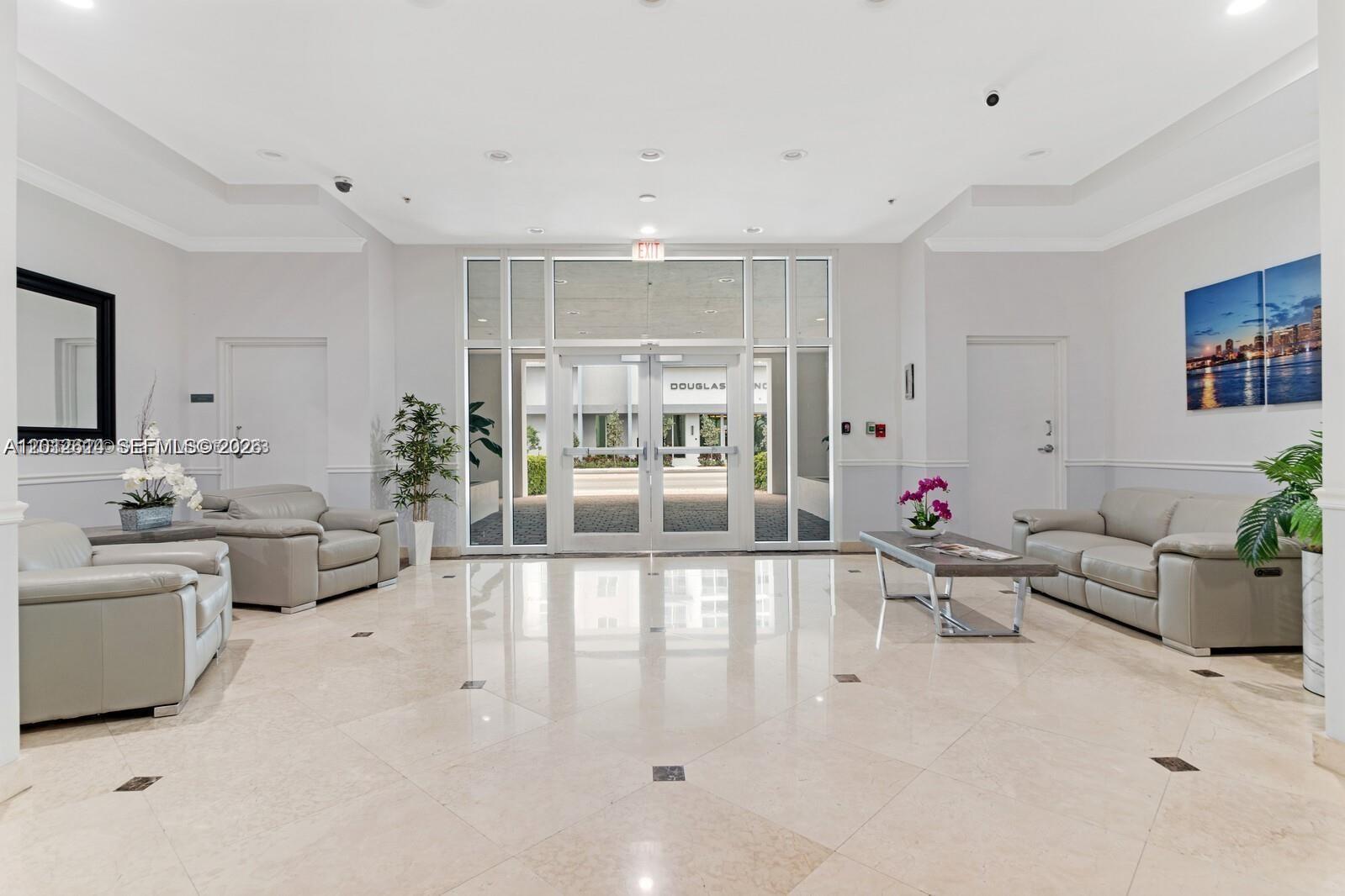 A bright lobby features light-colored tile floors, two leather sofas, and glass double entry doors — 60 NW 37th Ave # 1208, Miami FL 33125, MIAMI, FL