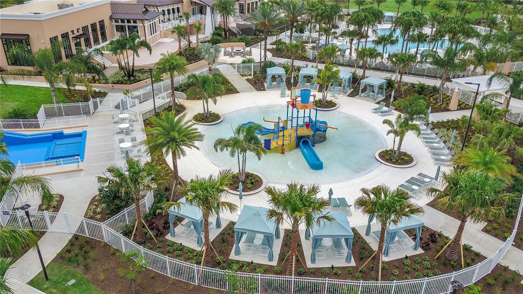 An aerial view shows a resort-style swimming pool complex with a central water play structure — 8914 CAROLINE BAY COURT, KISSIMMEE, FL