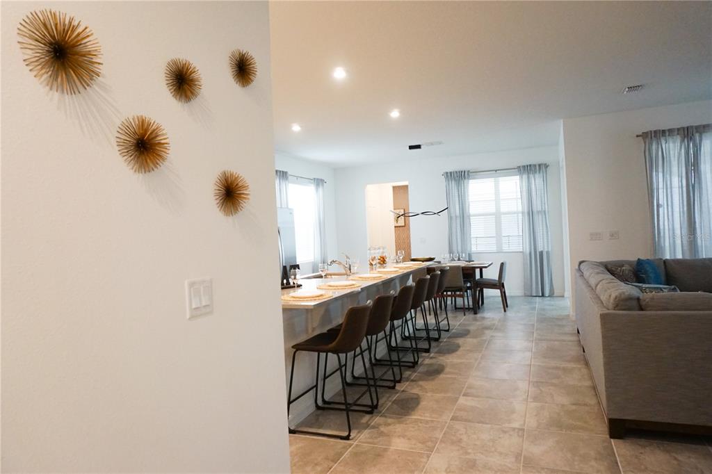 An open-concept kitchen with a breakfast bar and dining area overlooks a living room — 8914 CAROLINE BAY COURT, KISSIMMEE, FL