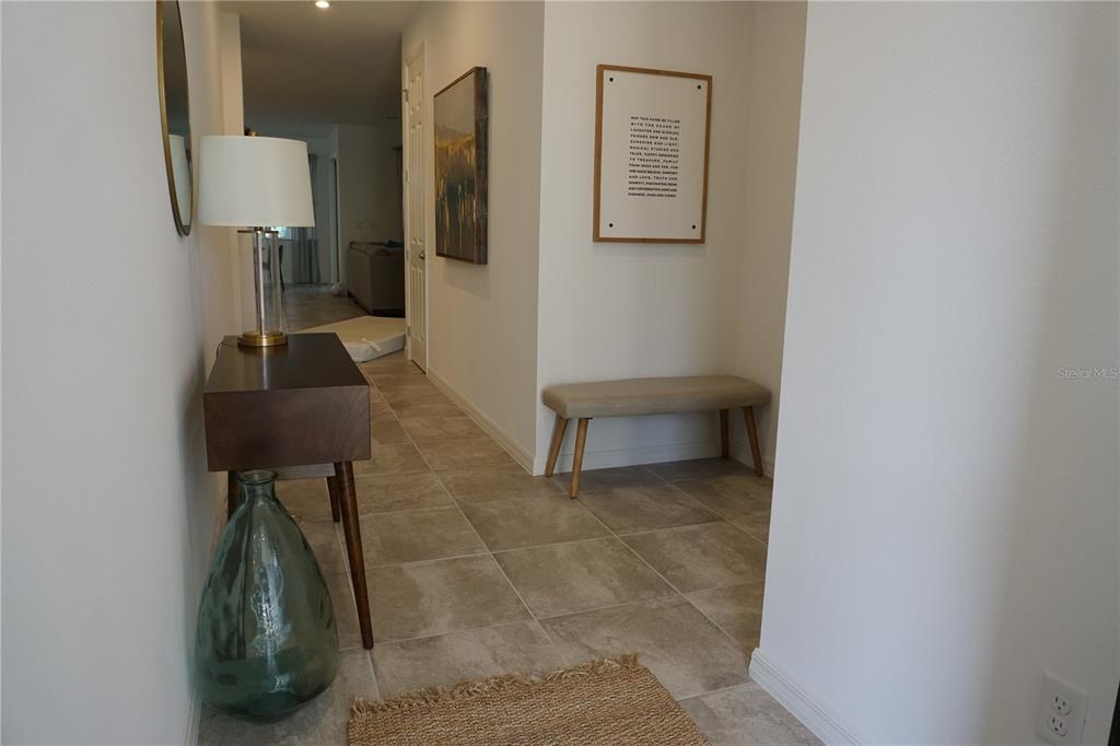 A bright entryway features tile flooring, a wooden console table with a lamp, and a bench — 8914 CAROLINE BAY COURT, KISSIMMEE, FL