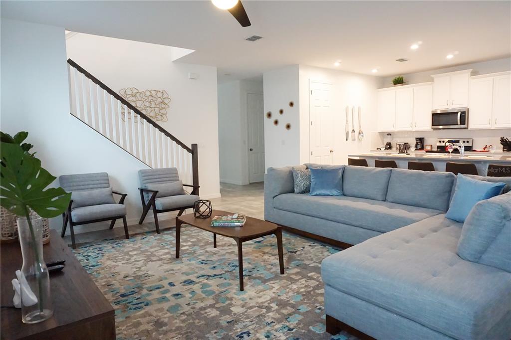 A living room with a sectional sofa, two armchairs, and an open kitchen — 8914 CAROLINE BAY COURT, KISSIMMEE, FL