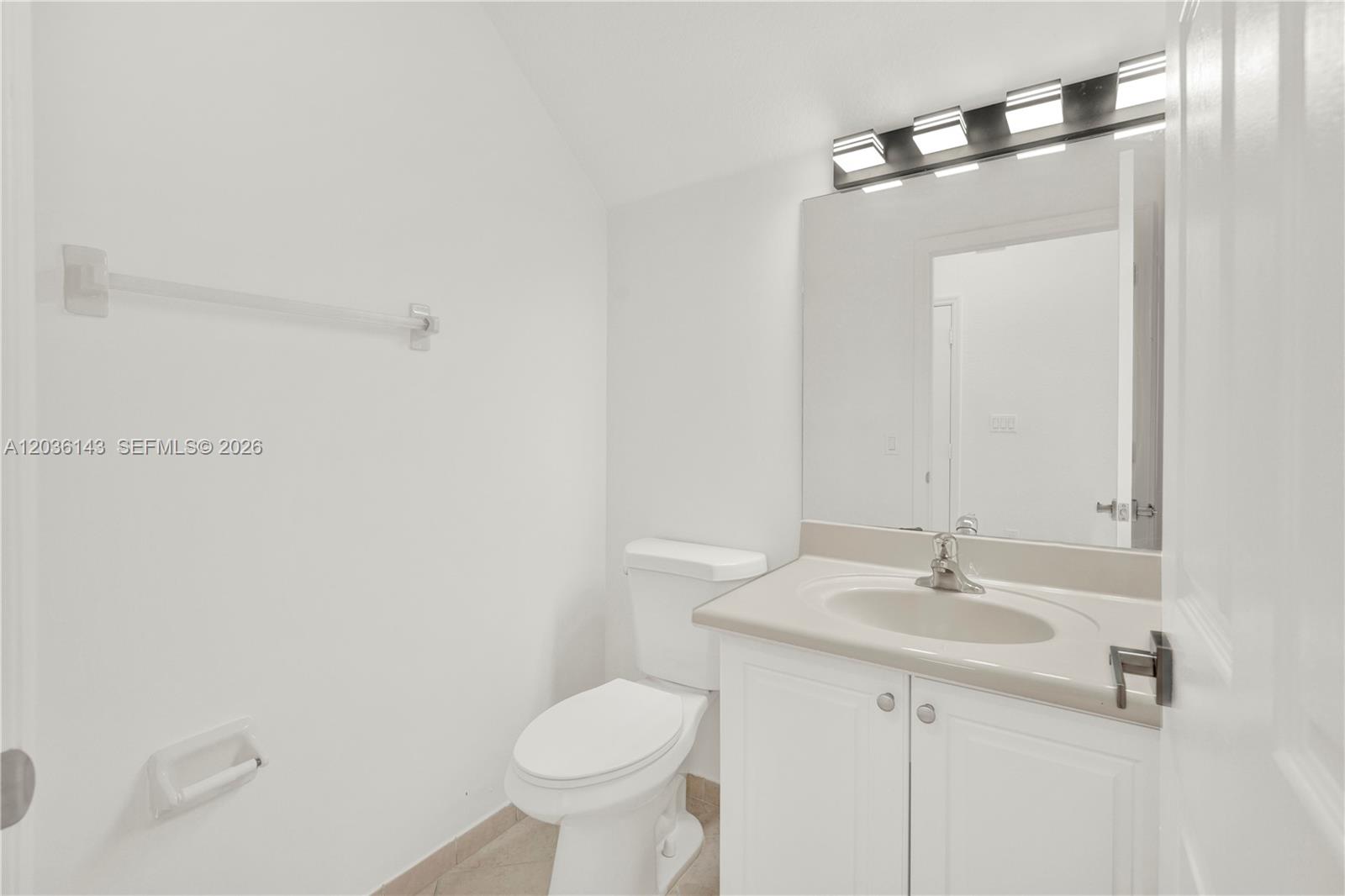 A bathroom features a white vanity, a toilet, and a wall-mounted mirror with lighting — 11467 SW 236th Ln, Homestead FL 33032, HOMESTEAD, FL