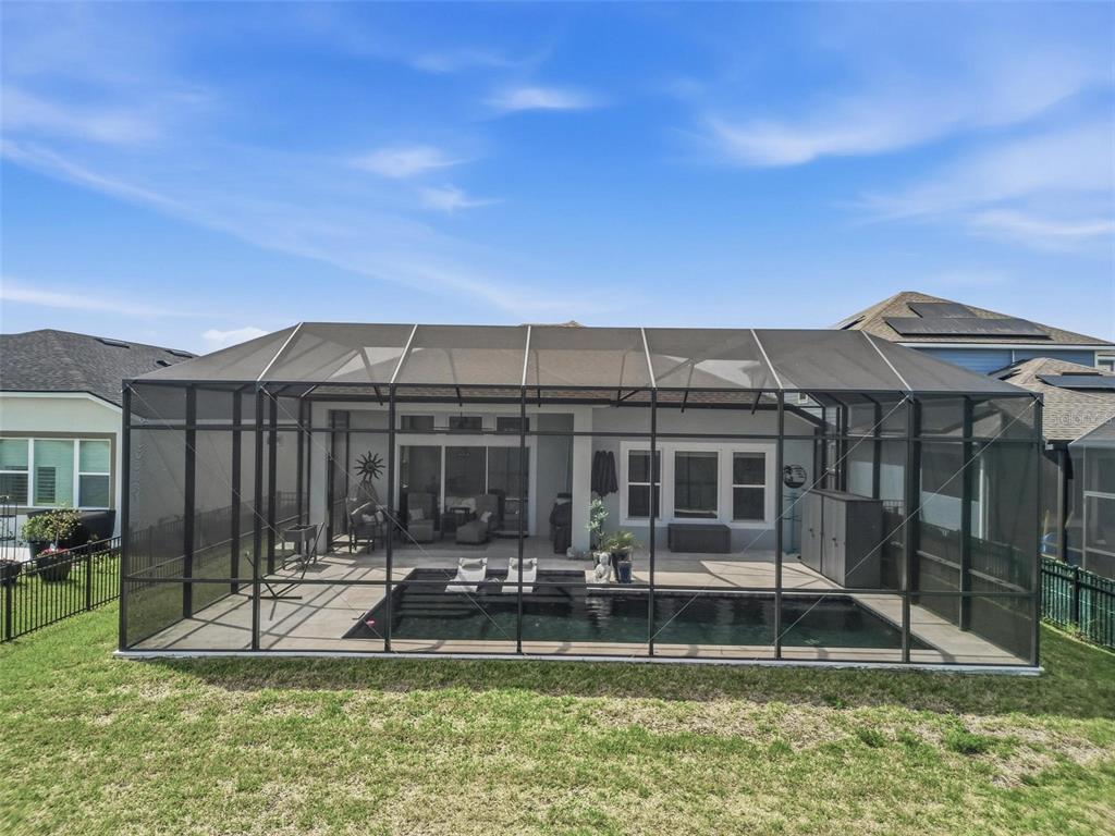 A screened-in patio features a rectangular swimming pool and a concrete deck behind a house — 270 AZURE MIST WAY, DAYTONA BEACH, FL