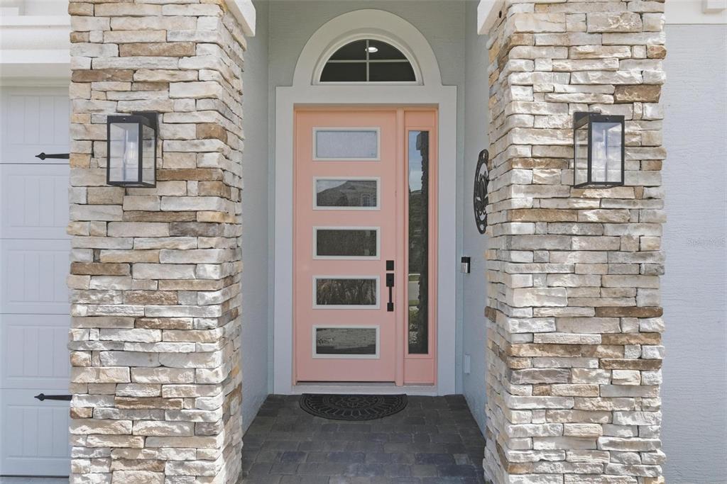 A peach-colored front door with glass panels is flanked by two stone-clad pillars — 270 AZURE MIST WAY, DAYTONA BEACH, FL