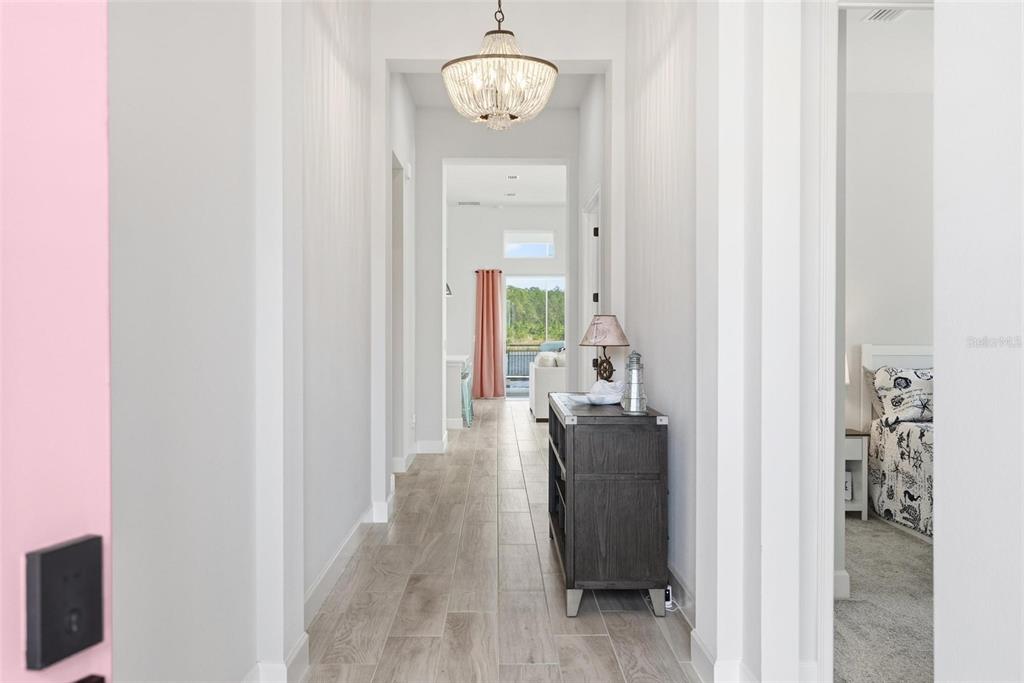 A hallway with light wood-look tile floors leads to an open living area with curtains — 270 AZURE MIST WAY, DAYTONA BEACH, FL