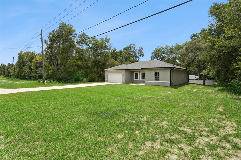 A single-story house with a two-car garage sits on a large, grassy lot — 799 W COUNTRY CLUB BOULEVARD, CITRUS SPRINGS, FL