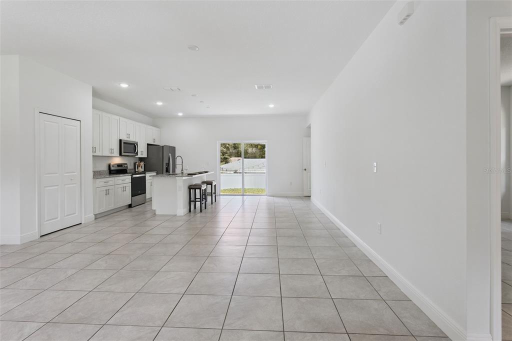 An open-concept kitchen and living area features white cabinetry, tile flooring, and sliding glass doors — 799 W COUNTRY CLUB BOULEVARD, CITRUS SPRINGS, FL