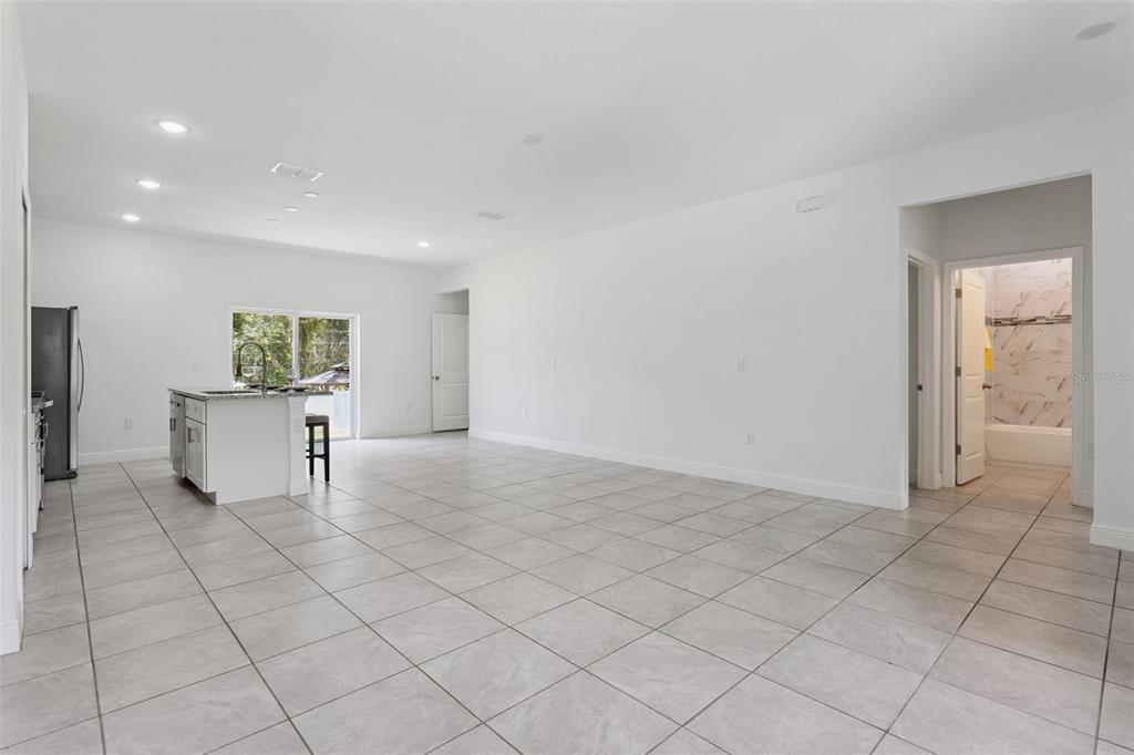 A spacious, open-concept room features white walls, large light-colored floor tiles, and a kitchen island — 799 W COUNTRY CLUB BOULEVARD, CITRUS SPRINGS, FL
