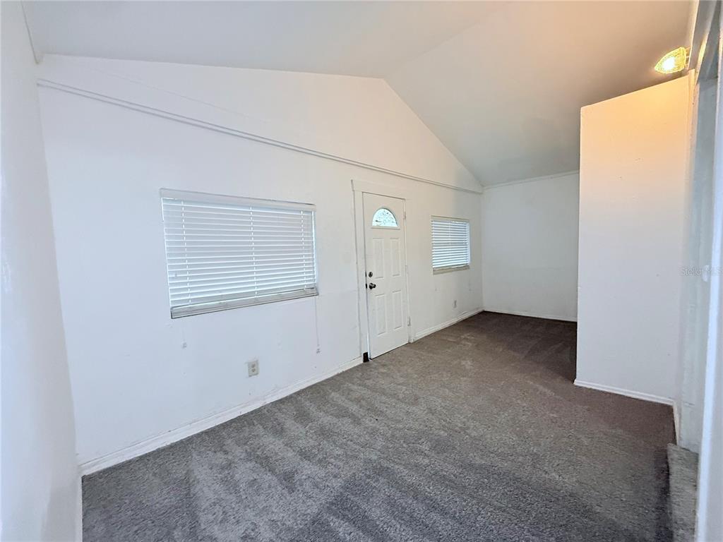 An empty room with white walls, gray carpeting, a vaulted ceiling, and a white door — 405 E DR. MARTIN LUTHER KING JR. BOULEVARD, TAMPA, FL
