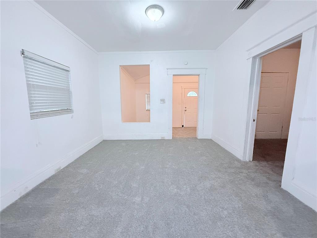 An empty room features gray carpet, white walls, a window with blinds, and two doorways — 405 E DR. MARTIN LUTHER KING JR. BOULEVARD, TAMPA, FL