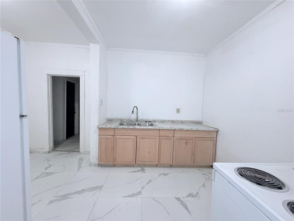 A kitchen features light wood cabinets, a granite countertop, and white marble-patterned tile flooring — 405 E DR. MARTIN LUTHER KING JR. BOULEVARD, TAMPA, FL