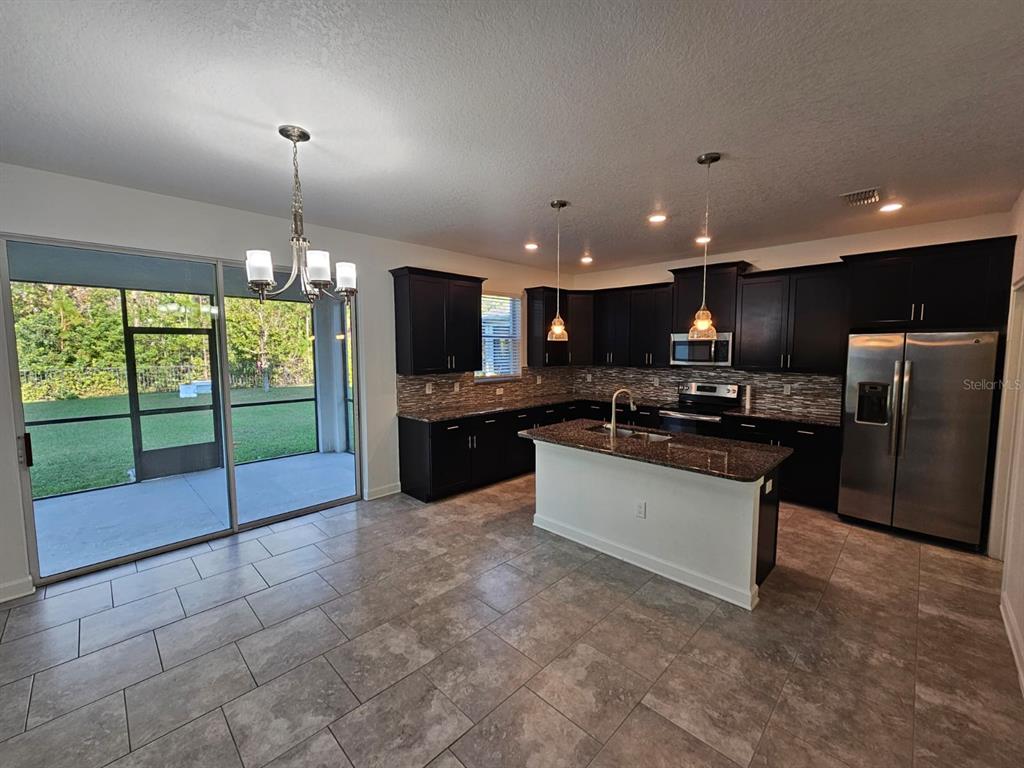 A kitchen with dark cabinets, granite countertops, a center island, and sliding glass patio doors — 3059 BEAVER CREEK DRIVE, KISSIMMEE, FL