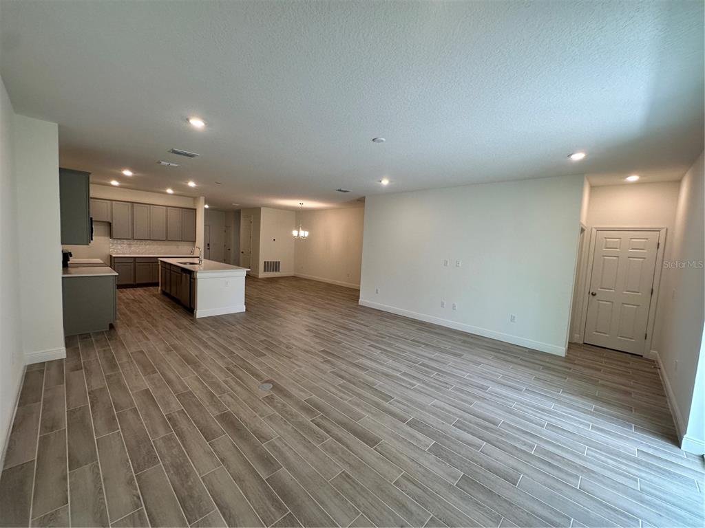 An open-concept kitchen with gray cabinets and a white island overlooks a large living area — 24 BALLARD LANE, PALM COAST, FL