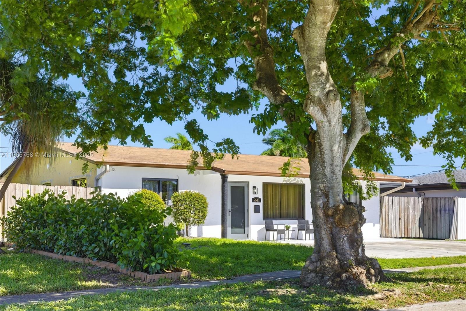 A white single-story house features a large tree in the front yard — 7511 Taylor St, Hollywood FL 33024, HOLLYWOOD, FL