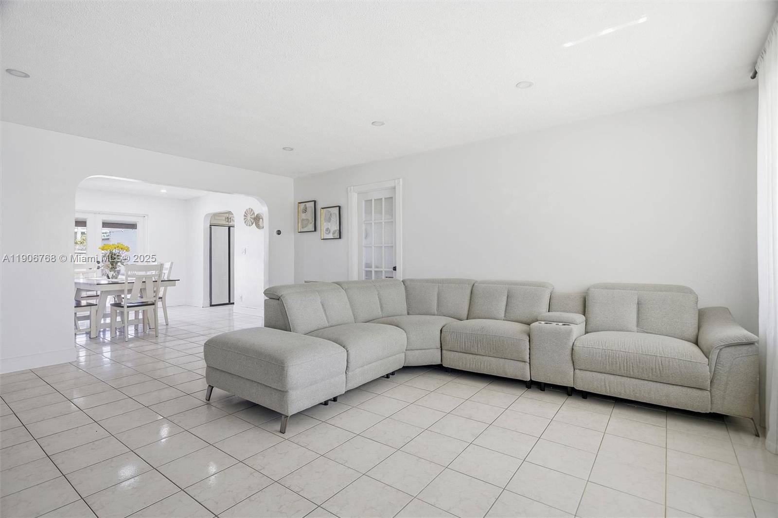 A light-colored sectional sofa sits on a tiled floor in a bright living room — 7511 Taylor St, Hollywood FL 33024, HOLLYWOOD, FL