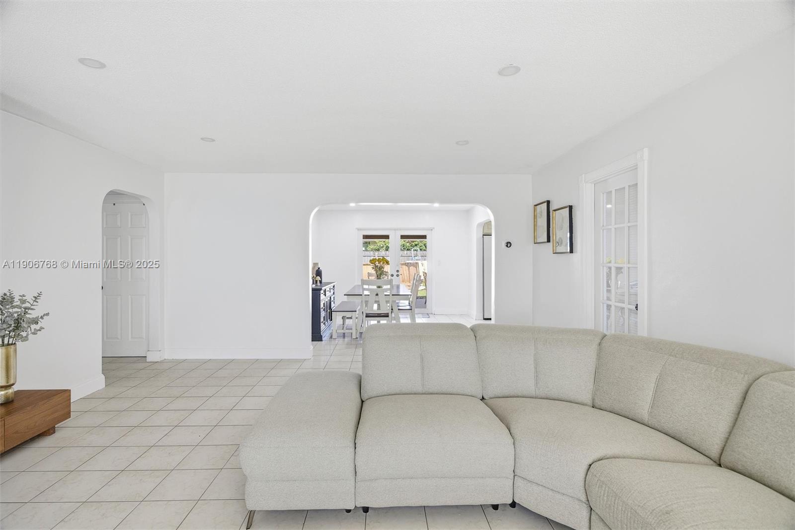 A living room with light tile floors, white walls, and a large sectional sofa — 7511 Taylor St, Hollywood FL 33024, HOLLYWOOD, FL