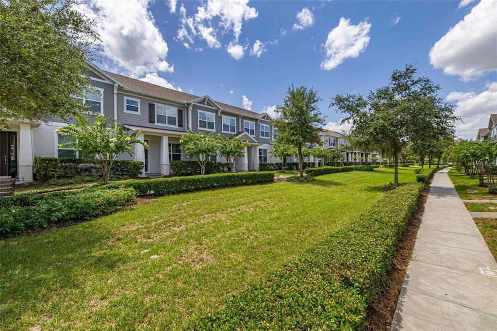 A row of two-story townhomes with gray siding sits behind a manicured lawn and hedge — 11193 HANLON TERRACE ALLEY, WINTER GARDEN, FL
