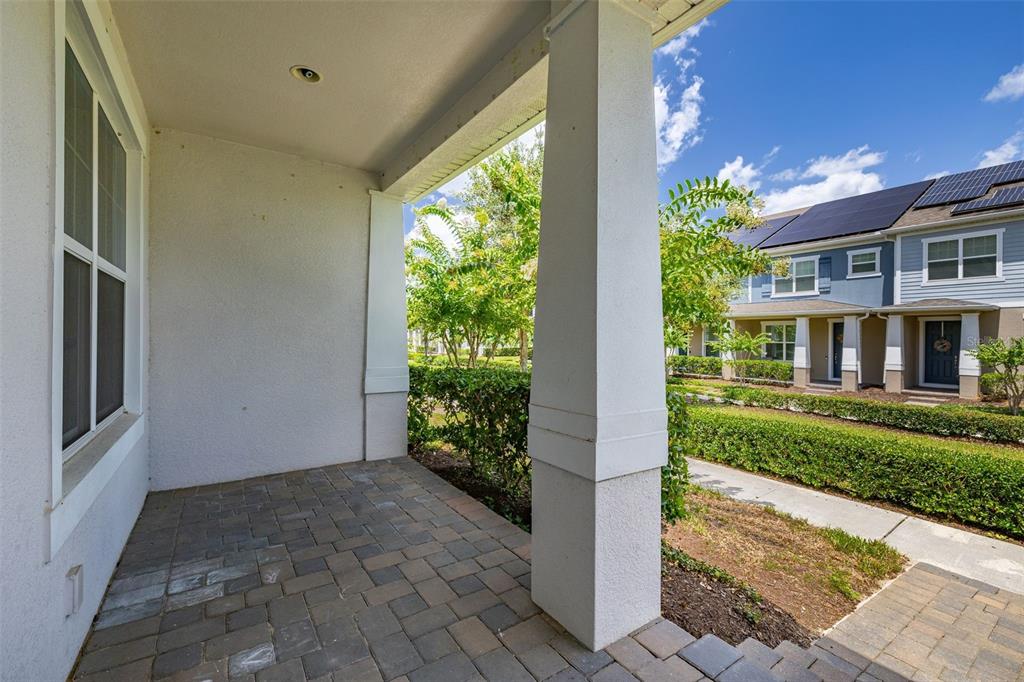 A covered porch with paver flooring overlooks a landscaped yard and neighboring townhomes — 11193 HANLON TERRACE ALLEY, WINTER GARDEN, FL