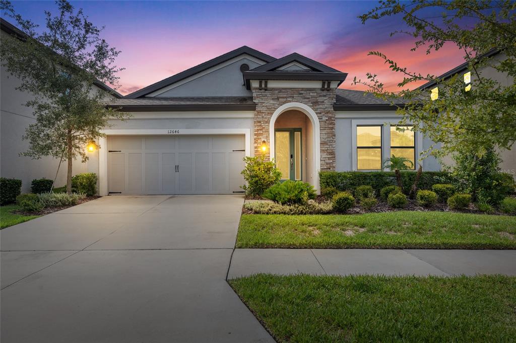 A single-story house with a stone-accented entryway, a two-car garage, and a landscaped front yard — 12646 SHETLAND WALK DRIVE, LITHIA, FL