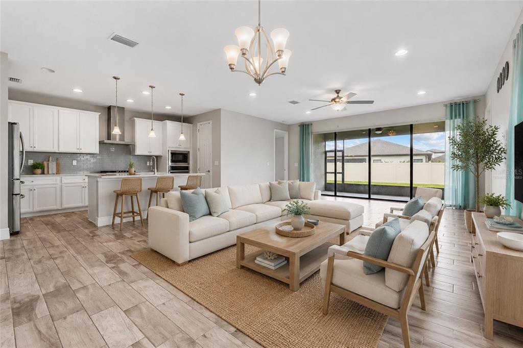 An open-concept living room and kitchen featuring white cabinetry, a sectional sofa, and tile flooring — 12646 SHETLAND WALK DRIVE, LITHIA, FL