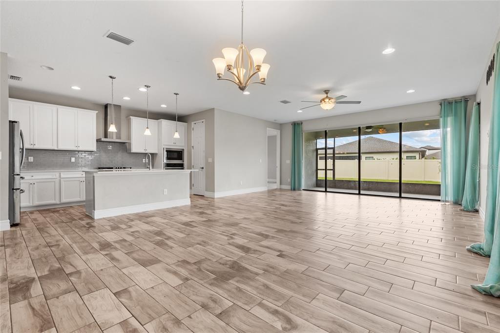 A bright open-concept kitchen and living area with white cabinets, tile floors, and sliding doors — 12646 SHETLAND WALK DRIVE, LITHIA, FL