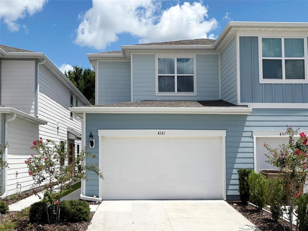 A two-story blue house with a white garage door and a concrete driveway — 4581 SPARKLING SHELL AVE, KISSIMMEE, FL