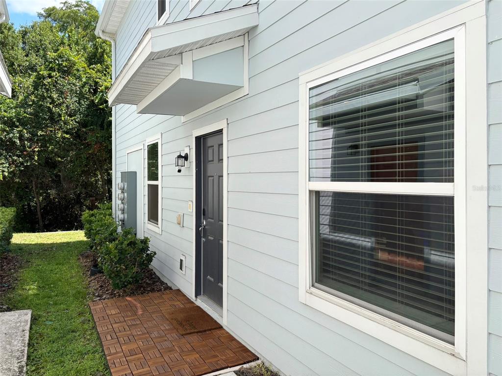 The exterior of a light blue house features a dark front door and tiled entryway — 4581 SPARKLING SHELL AVE, KISSIMMEE, FL