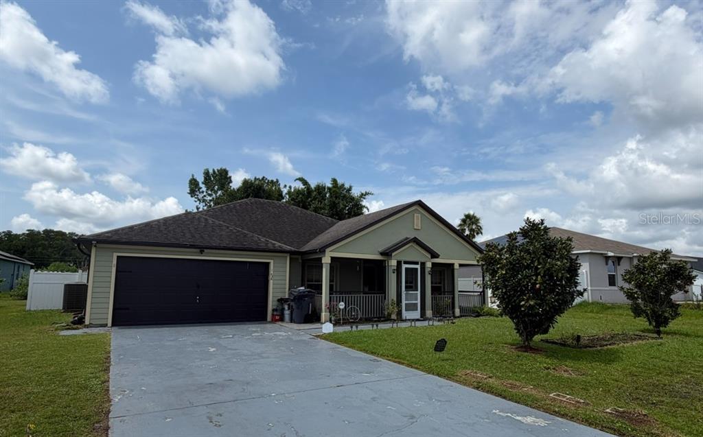 A single-story house with a dark garage door, a covered porch, and a concrete driveway — 426 BAR COURT, POINCIANA, FL