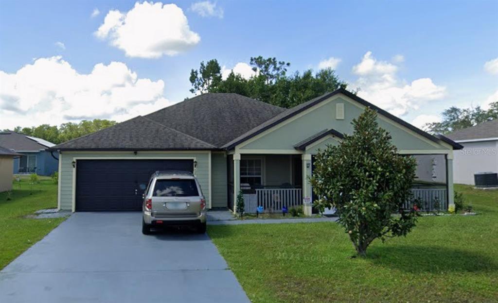 A single-story house with light green siding, a two-car garage, and a front porch — 426 BAR COURT, POINCIANA, FL