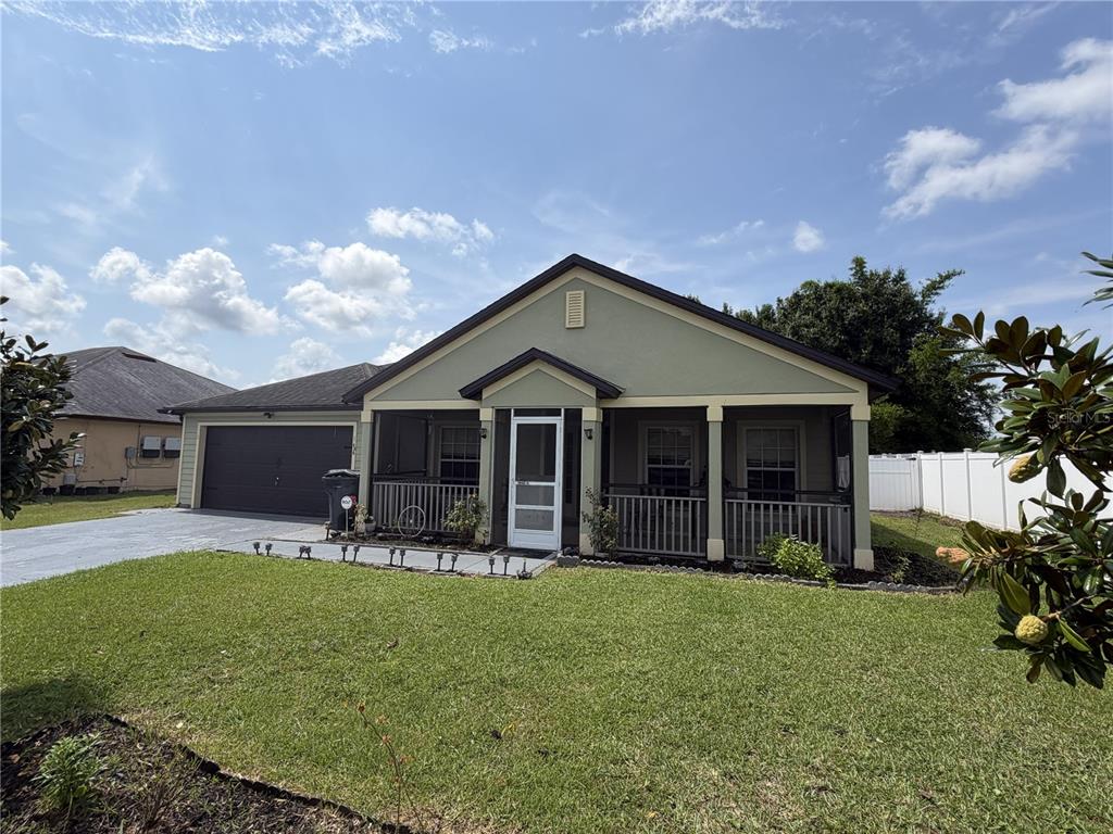 A single-story house with a screened front porch, a two-car garage, and a grassy lawn — 426 BAR COURT, POINCIANA, FL