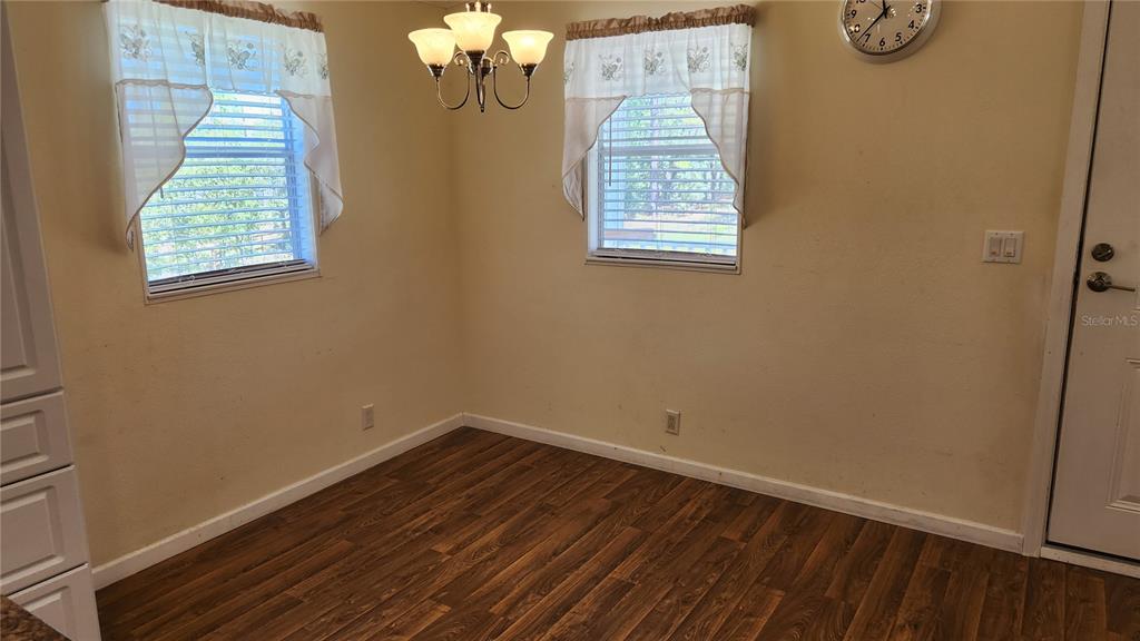 A dining area features wood-look flooring, two windows with valances, a chandelier, and a clock — 2251 SE 146TH CIRCLE, MORRISTON, FL