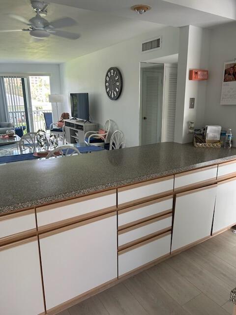 A kitchen counter with white cabinets and wood trim overlooks a living room with furniture — 2760 Banyan Road # 25a, Boca Raton FL 33432, BOCA RATON, FL