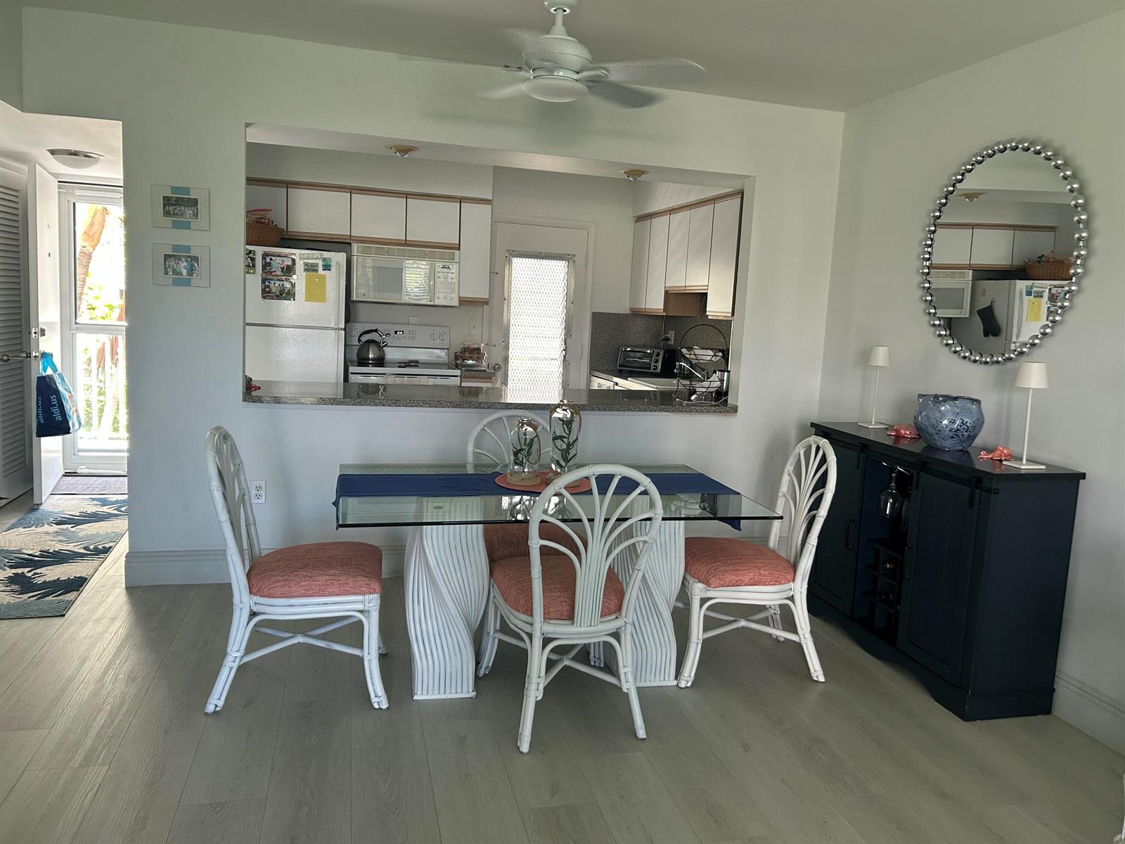 A dining area features a glass-top table with white wicker chairs and a dark sideboard — 2760 Banyan Road # 25a, Boca Raton FL 33432, BOCA RATON, FL