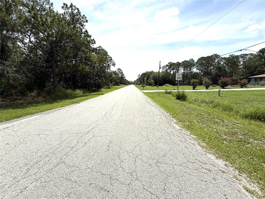 A paved road stretches into the distance past a speed limit sign and wooded area — 0 LAKE CALOOSA LANDING, FROSTPROOF, FL