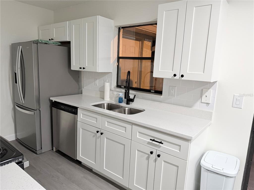 A kitchen features white shaker cabinets, stainless steel appliances, a double sink, and white countertops — 6266 YORKTOWN DRIVE UNIT 179, ORLANDO, FL