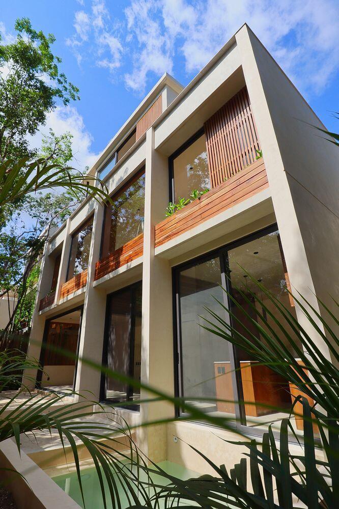 A modern three-story house exterior features large glass windows, wood slat accents, and a pool — Amari Tulum 10 Avenida Norte & Calle Palma, FL