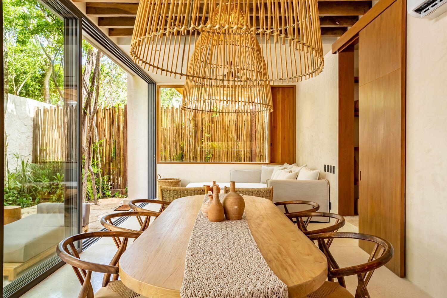 A dining room features a wooden table, woven chairs, and a large bamboo pendant light — Amari Tulum 10 Avenida Norte & Calle Palma, FL