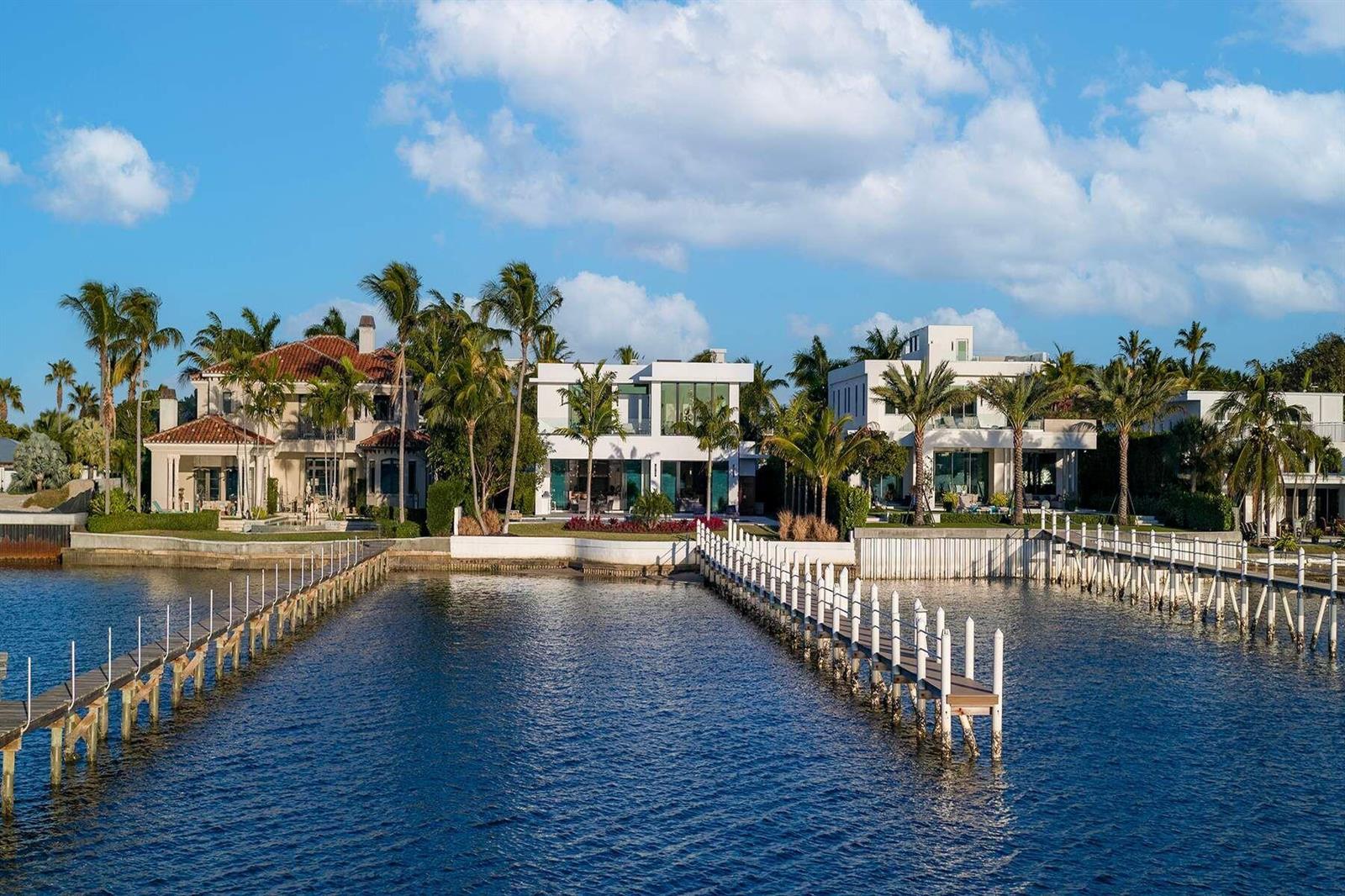 Three waterfront houses with docks and palm trees under a blue sky — 807 N Atlantic Drive, Lantana FL 33462, LANTANA, FL