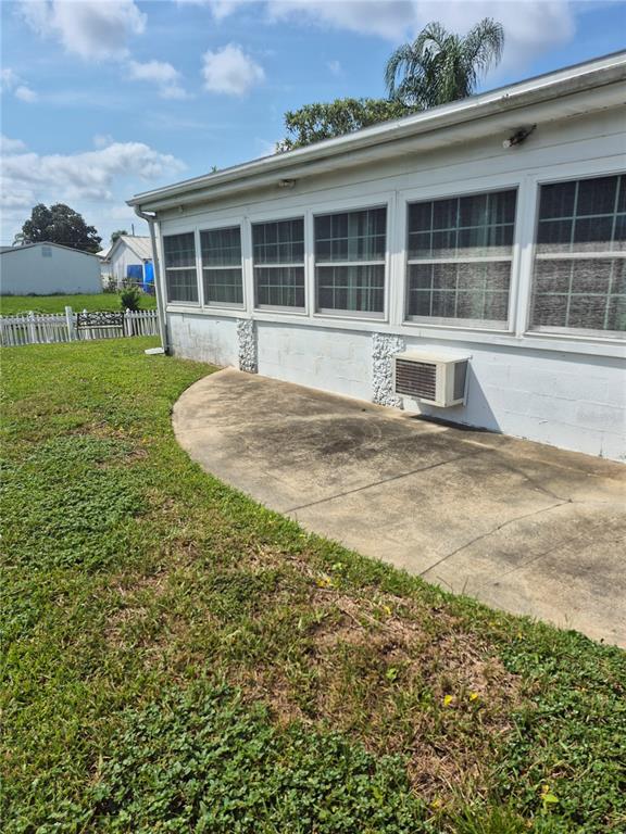 A concrete patio sits beside a white house with multiple windows and a wall-mounted air conditioner — 2604 REEF COURT, ORLANDO, FL
